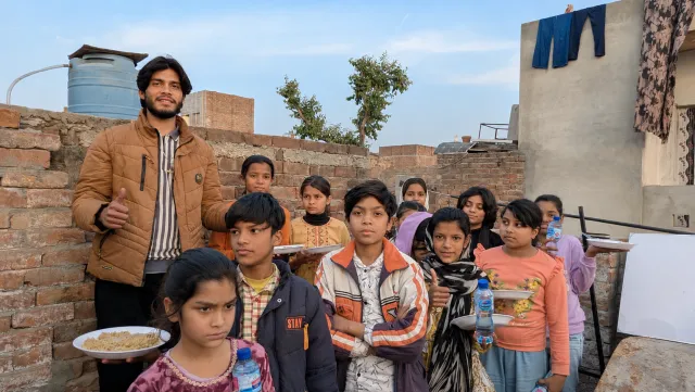 Children holding plates of food after a meal served at the academy